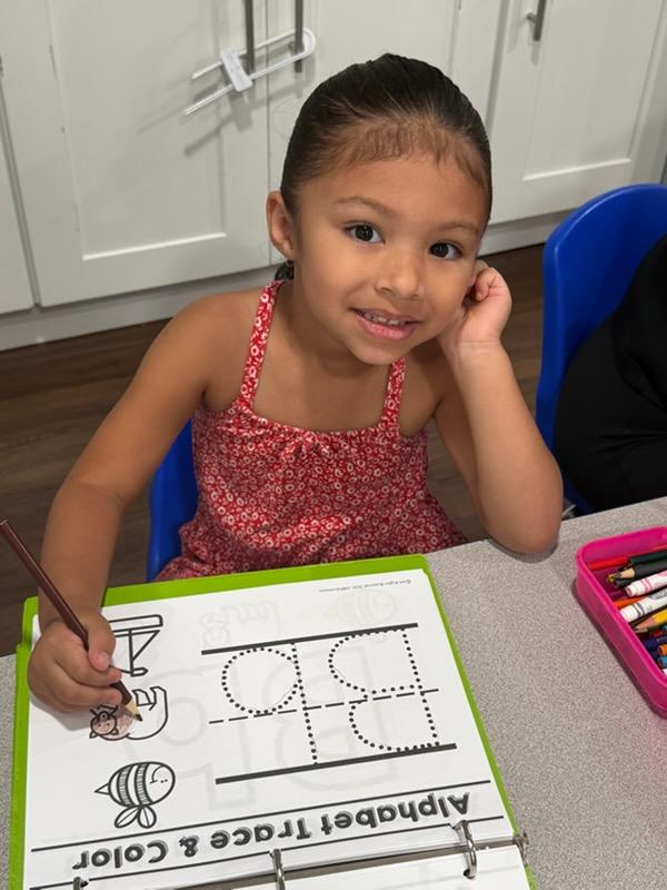 Girl coloring an alphabet trace and color worksheet