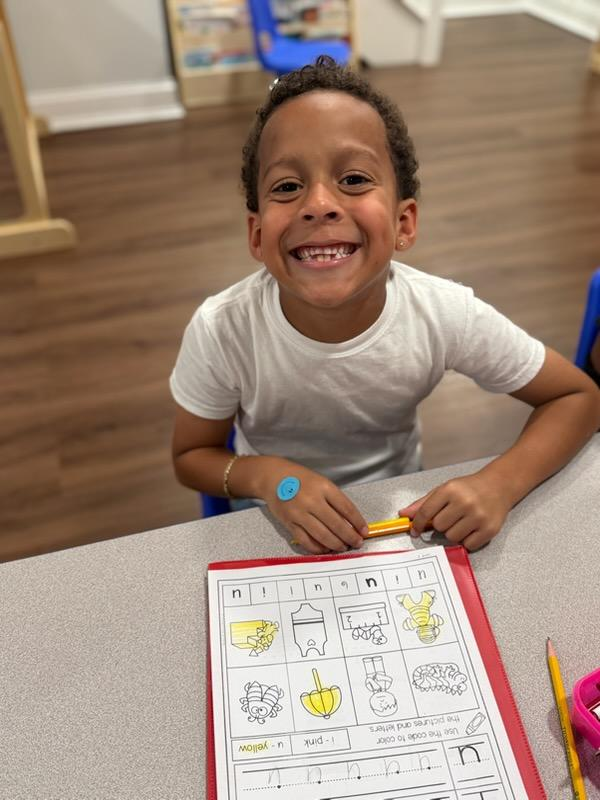 Child smiling while working on a phonics worksheet